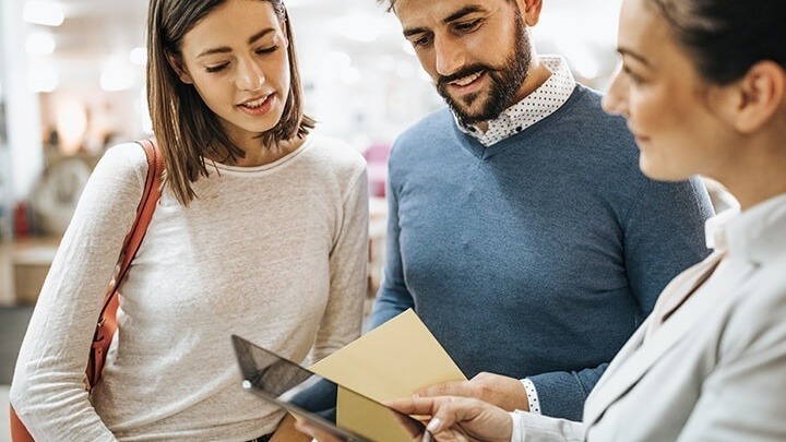 saleswoman with a tablet consulting a couple in a furniture store