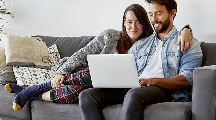 couple sharing a laptop in their living room