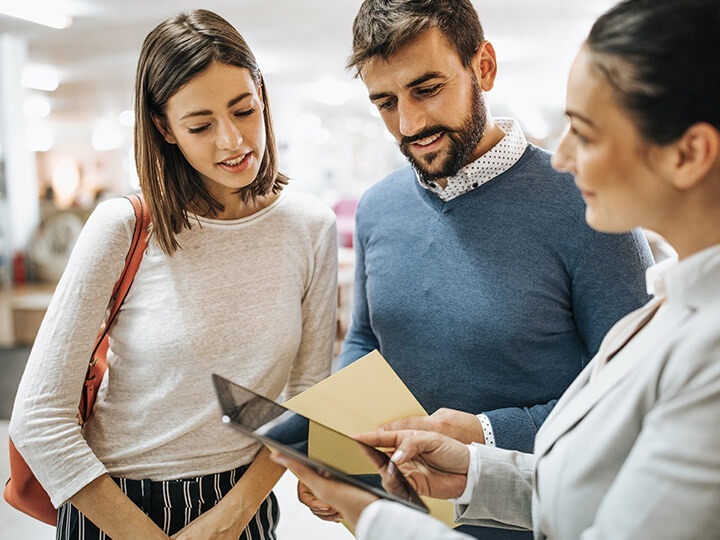 saleswoman with young couple in store with a tablet