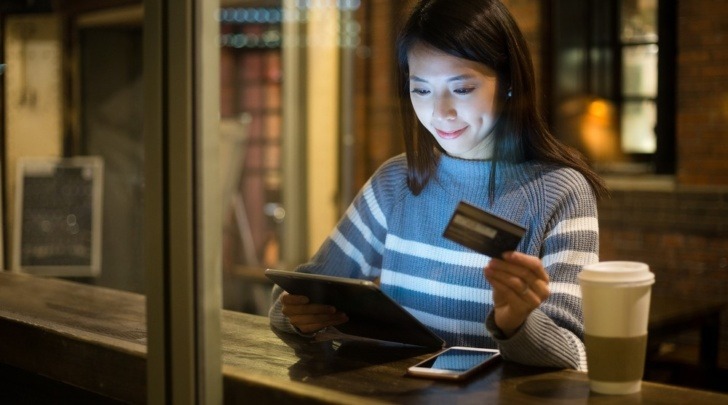 young woman paying with credit card online in a cafe