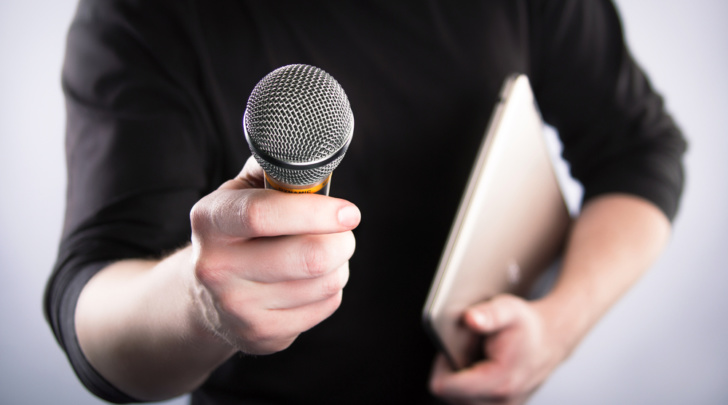 man holding a microphone and notebook